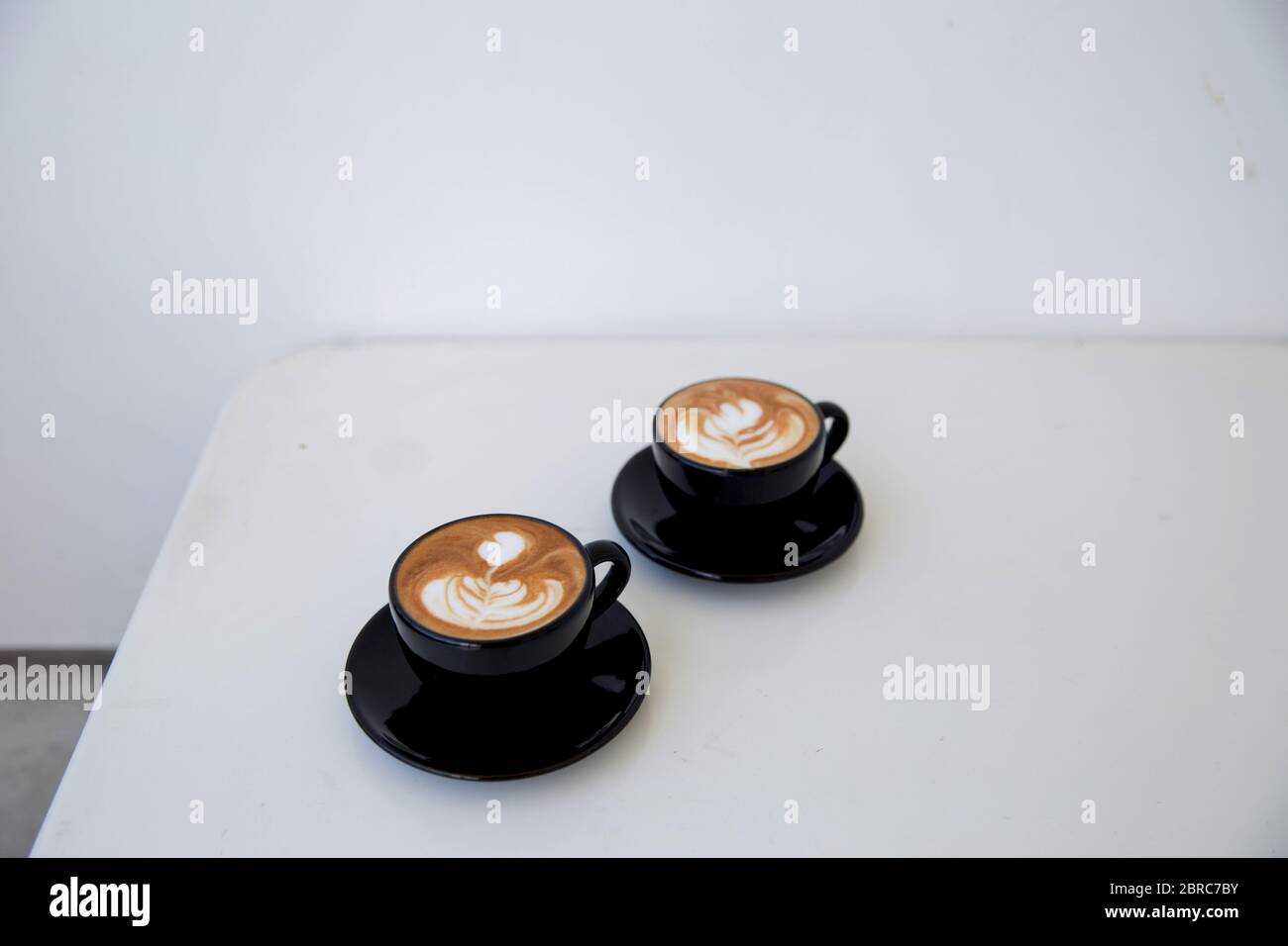 Zwei Tassen heißen Cappuccino auf weißem Holztisch Hintergrund. Platz für Text. Stockfoto