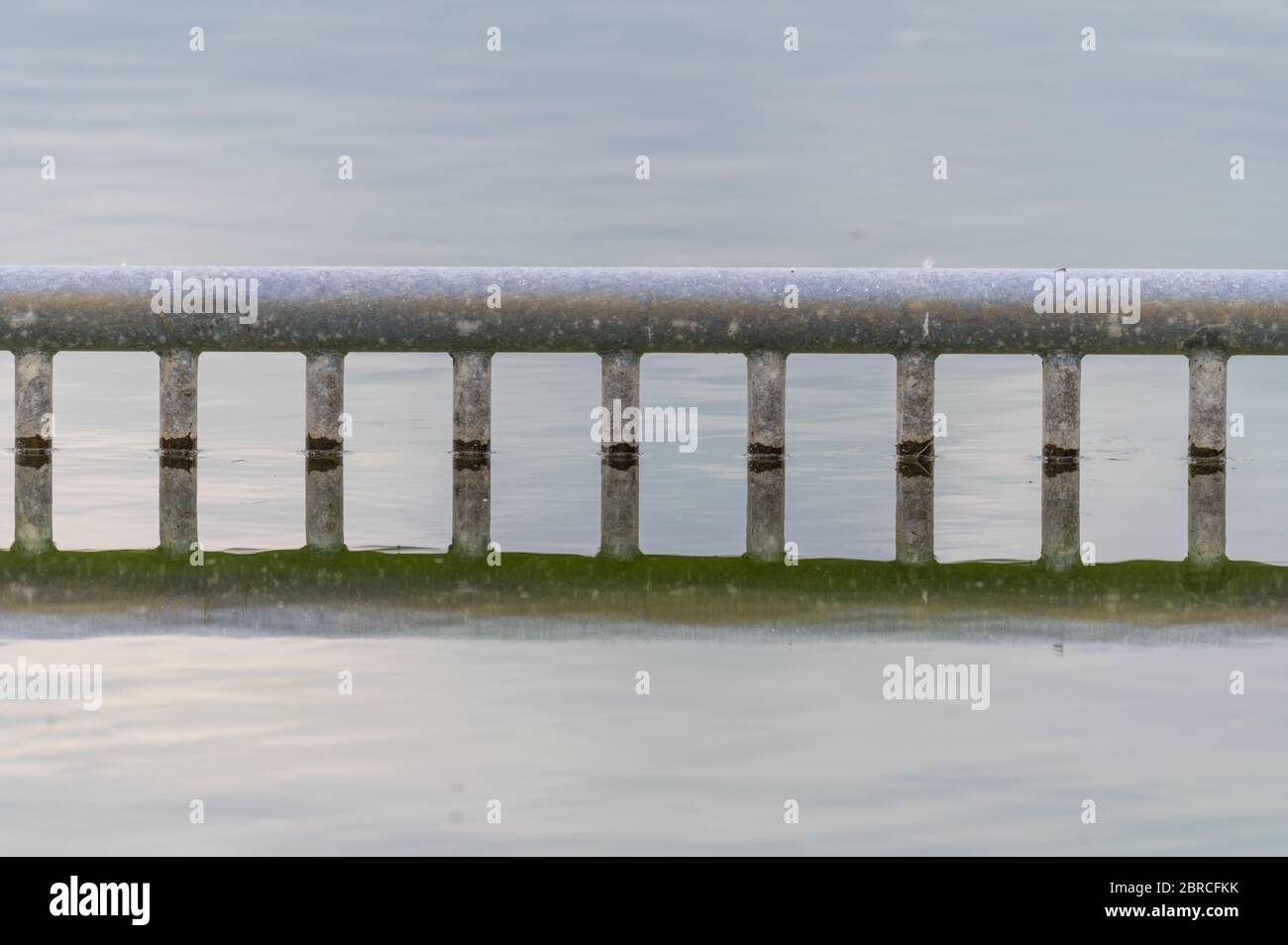 Blick auf einen Steinbruchteich mit besonderem Fokus auf eine reflektierende Markierung für Nichtschwimmer vom Ufer aus mit bewölktem Himmel und ruhigem Wasser im nördlichen Germa Stockfoto