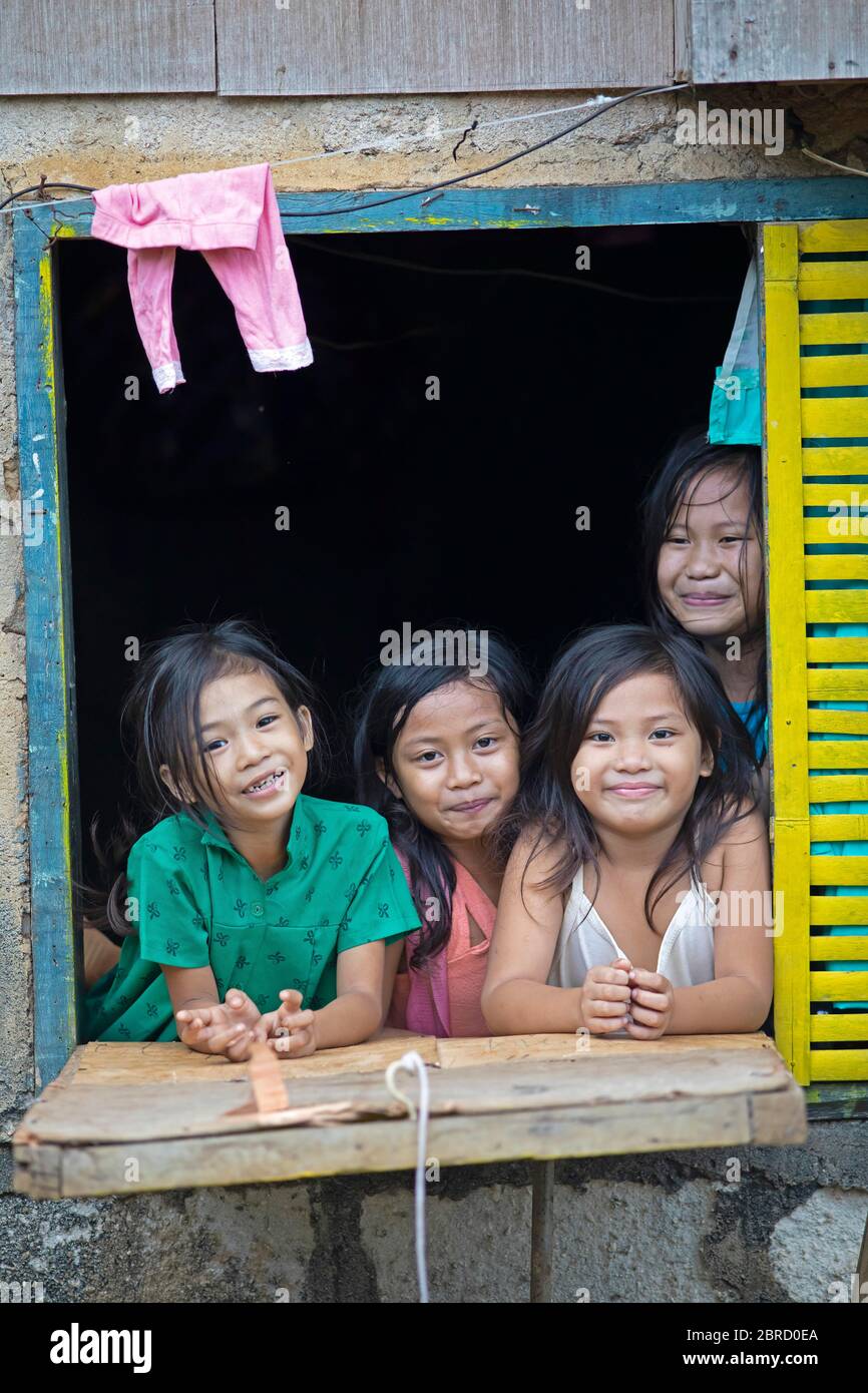 Glückliche Kinder, die aus dem Fenster ihres Hauses schauen, Anda, Bohol, Central Visayas, Philippinen Stockfoto