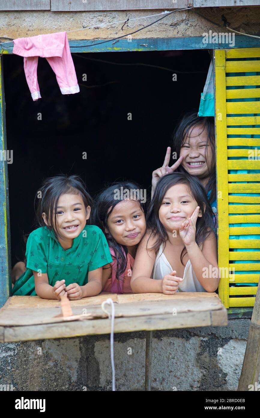 Glückliche Kinder, die aus dem Fenster ihres Hauses schauen, Anda, Bohol, Central Visayas, Philippinen Stockfoto