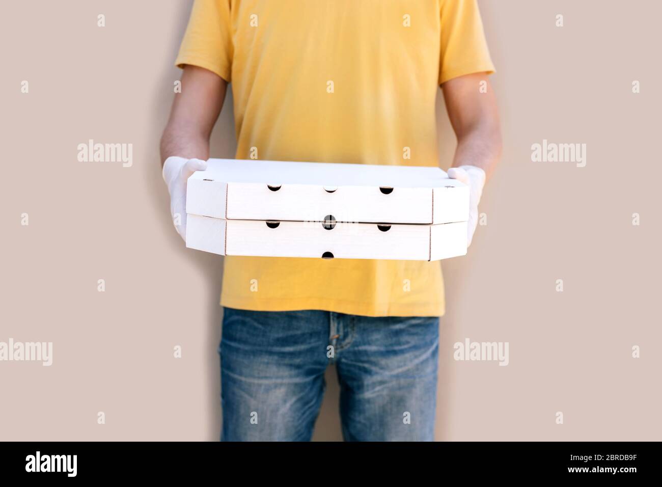 Mann aus dem Lieferservice in Schutzmaske und Handschuhe halten Pizza-Boxen. Stockfoto
