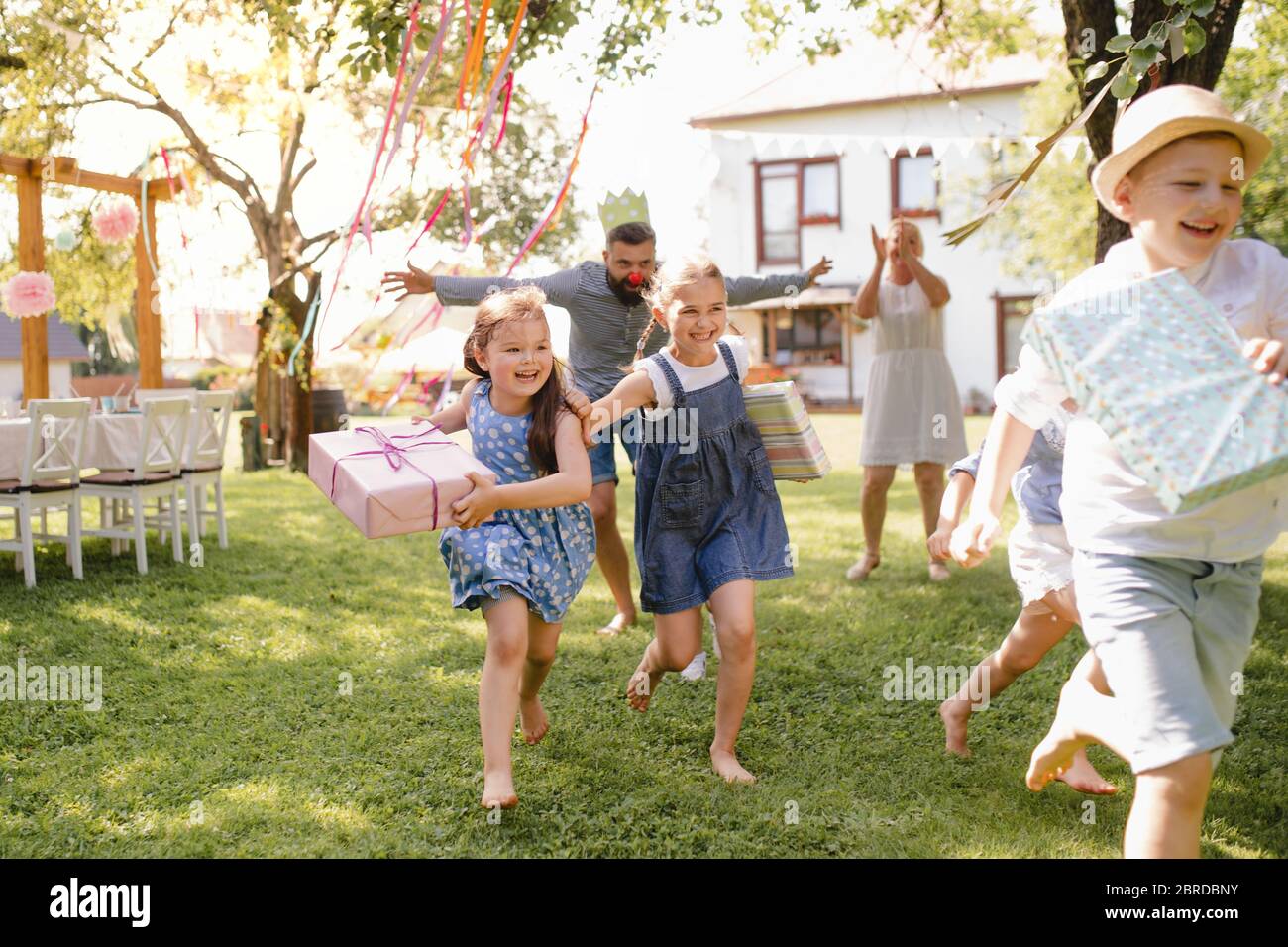 Kleine Kinder ruunning mit Geschenk im Garten auf Geburtstagsfeier. Stockfoto