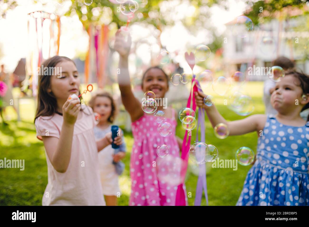 Kleine Kinder stehen im Sommer im Garten und spielen. Stockfoto
