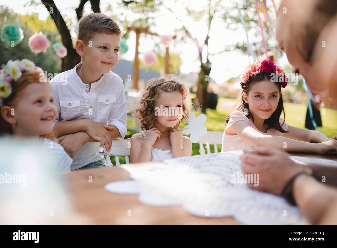 Kleine Kinder sitzen im Sommer auf Gartenparty am Tisch im Freien. Stockfoto