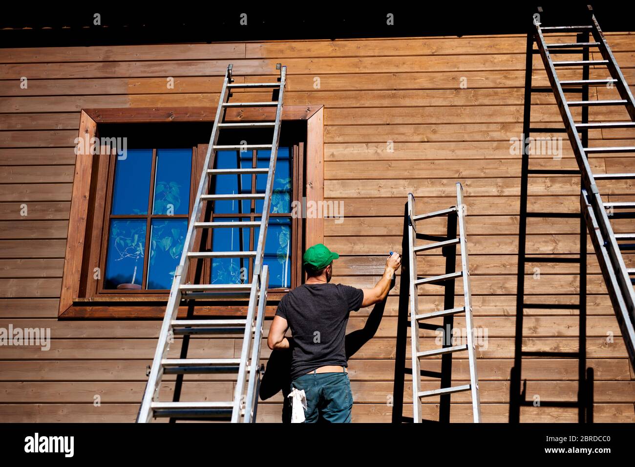 Ein reifer Mann im Freien im Sommer, Malerei Holzhaus. Stockfoto