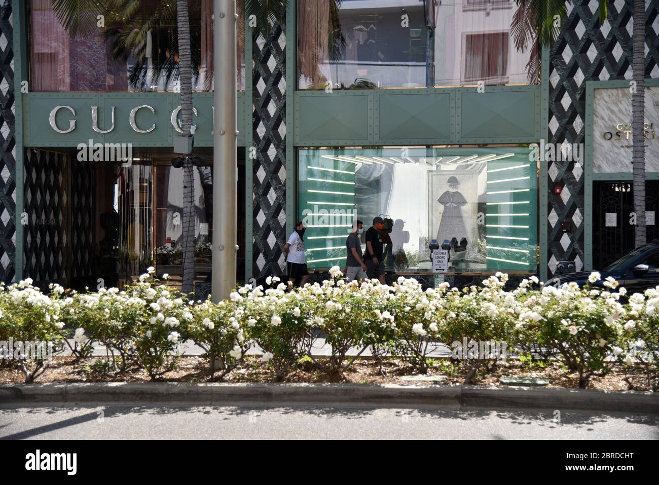 Beverly Hills, CA/USA - 8. Mai 2020: Männer in Gesichtsmasken gehen während der COVID-19 Quarantäne am Gucci Store auf dem Rodeo Drive vorbei Stockfoto
