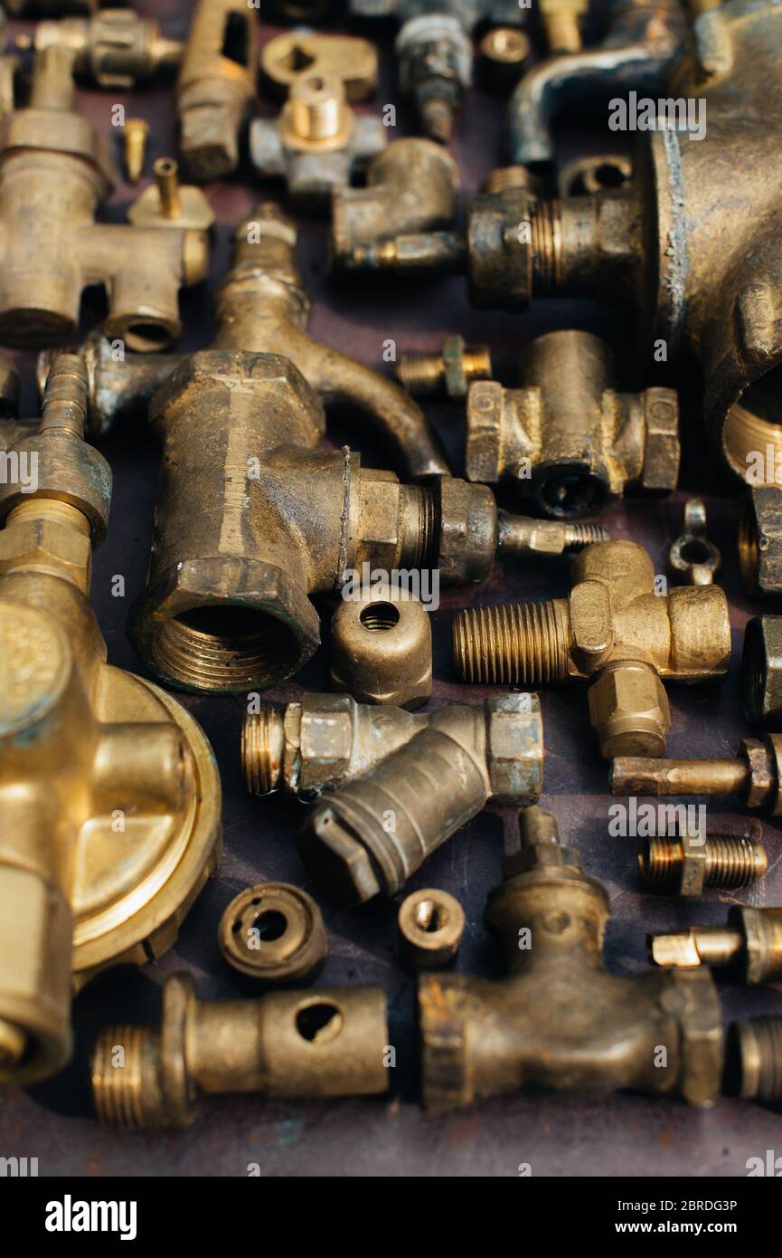Messing Altmetall: Armaturen, T-Stücke, Stecker und verschiedene Sanitär-Teile, Ersatzteile. Vor dem Hintergrund einer Kupferplatte. Nahaufnahme. Stockfoto