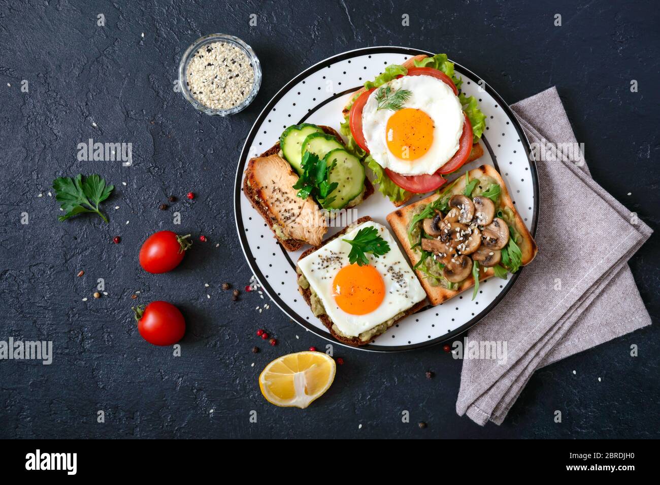 Verschiedene Sandwiches auf schwarzem Hintergrund. Leckere gesunde Vorspeise mit Avocado. Schnelles Frühstück. Gesundes Essen Konzept. Richtige Ernährung. Draufsicht Stockfoto