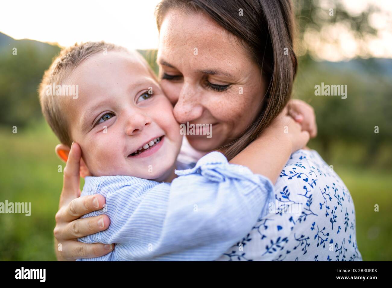 Mutter mit kleinen Kleinkind Sohn auf Spaziergang auf der Wiese im Freien, umarmt. Stockfoto