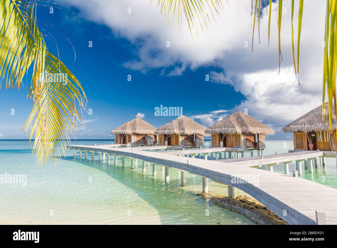 Wunderschöne tropische Malediven Resort Hotel Wasser Villen. Insel mit Strand und Palmenblättern über Meer am Himmel. Luxus Urlaub Urlaub Hintergrund Konzept Stockfoto