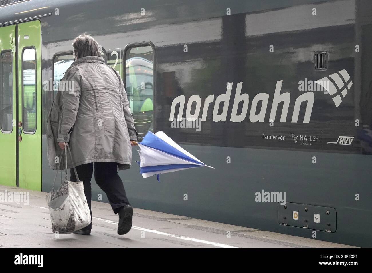 15. Mai 2020, Hamburg: Eine Frau mit Regenschirm läuft auf einem Zug der NBE nordbahn Eisenbahn-Verwaltungsgesellschaft mbH, der im Bahnhof Altona geparkt ist. Die nordbahn steht unter dem Dach der Verkehrsverbände Hamburg (HVV) und Schleswig-Holstein (nah.SH). Foto: Bodo-Marken/dpa/Bodo-Marken Stockfoto