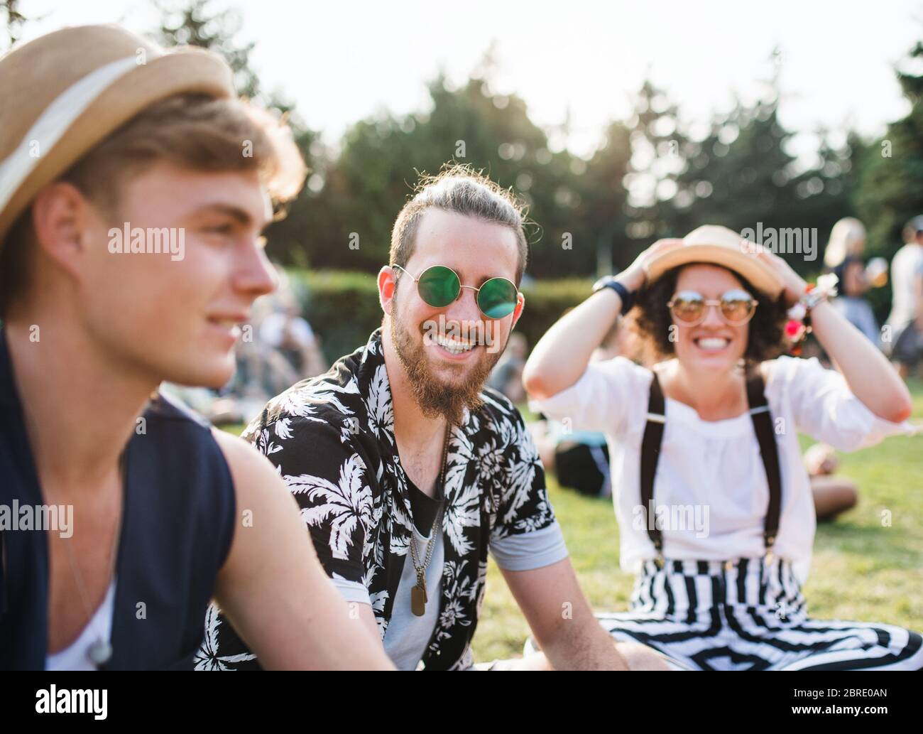 Gruppe junger Freunde, die auf dem Boden beim Sommerfest sitzen. Stockfoto