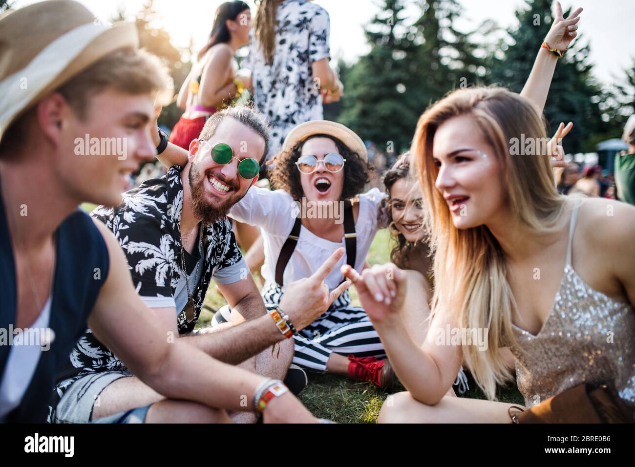 Gruppe junger Freunde, die auf dem Boden beim Sommerfest sitzen. Stockfoto