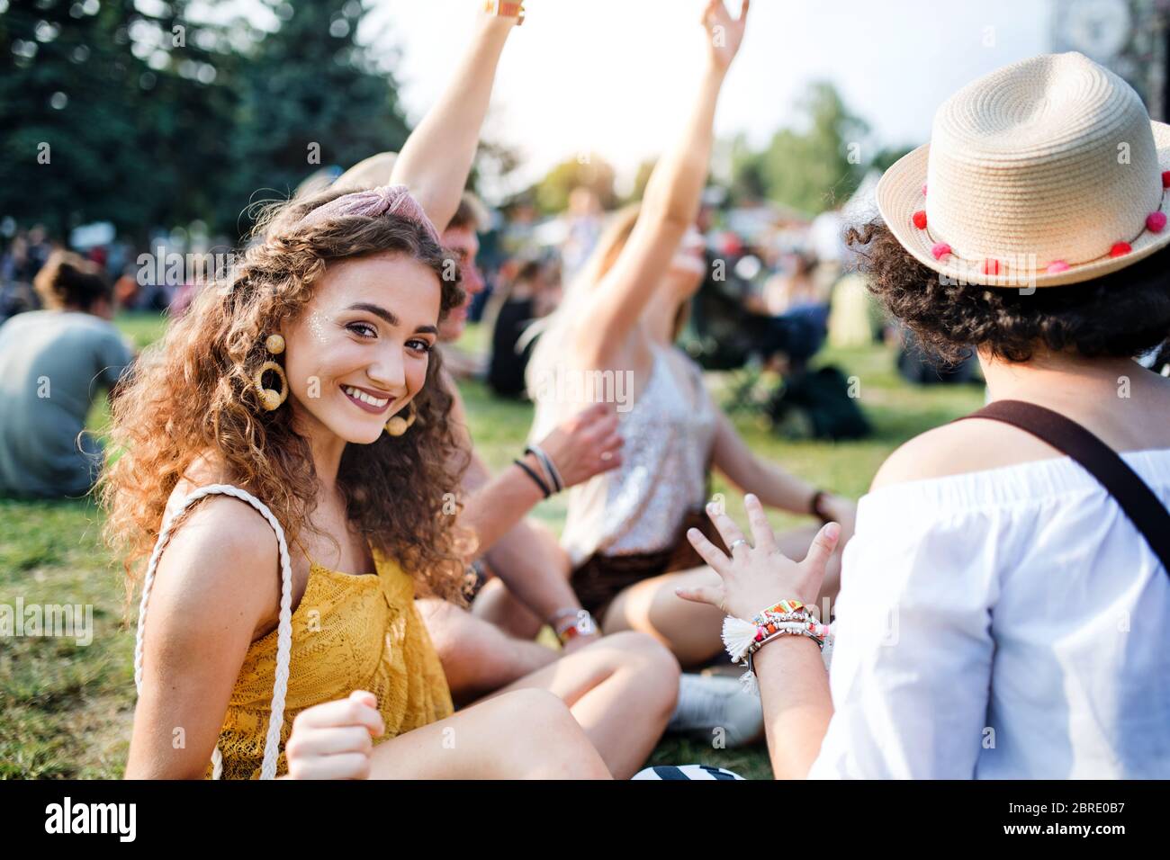 Gruppe junger Freunde, die auf dem Boden beim Sommerfest sitzen. Stockfoto