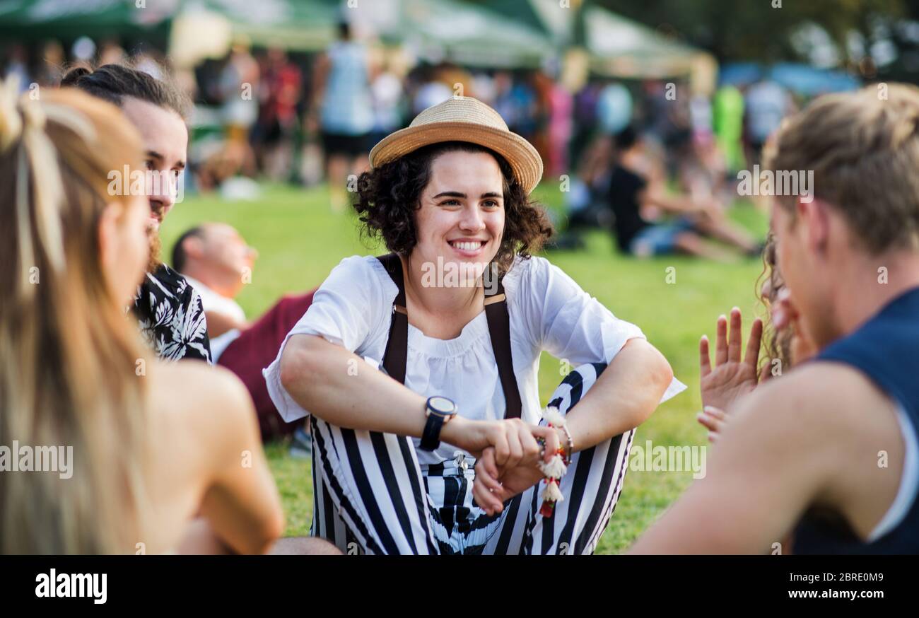 Gruppe junger Freunde, die auf dem Boden beim Sommerfest sitzen. Stockfoto