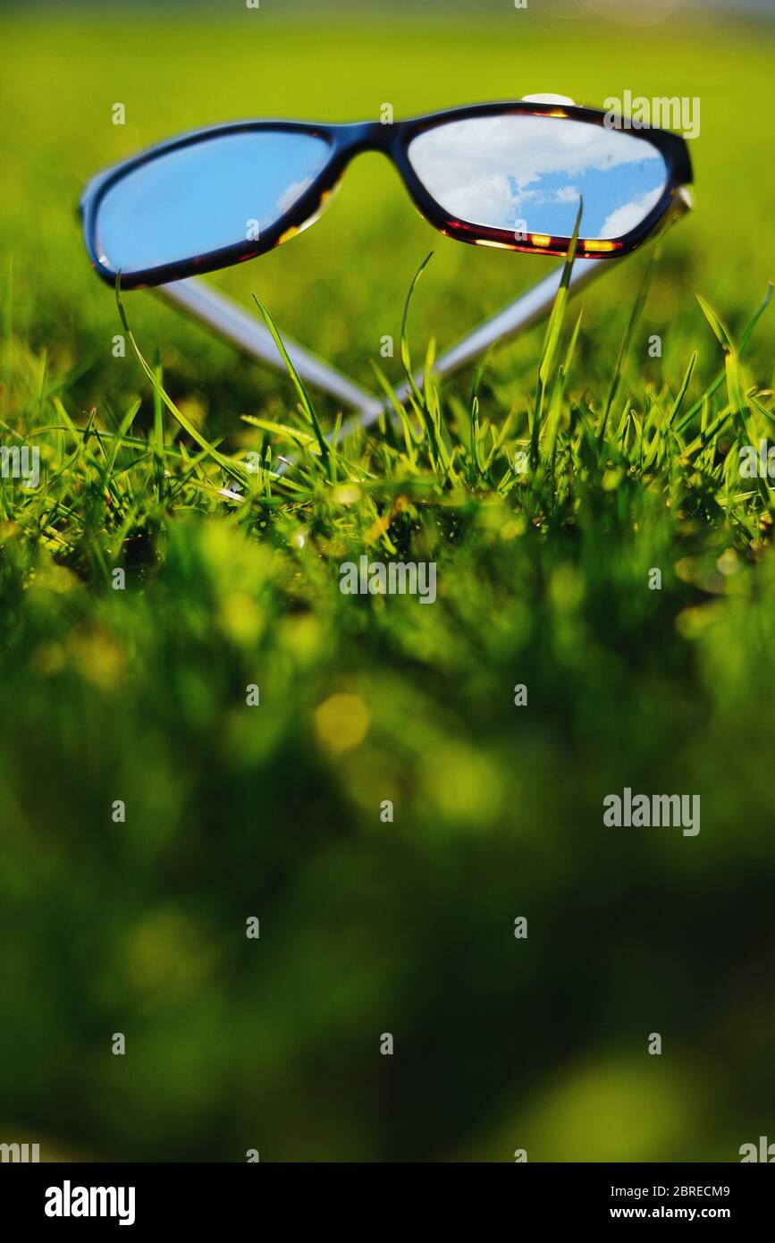 Sonnenbrille liegend Gras spiegelt den blauen Himmel Stockfoto