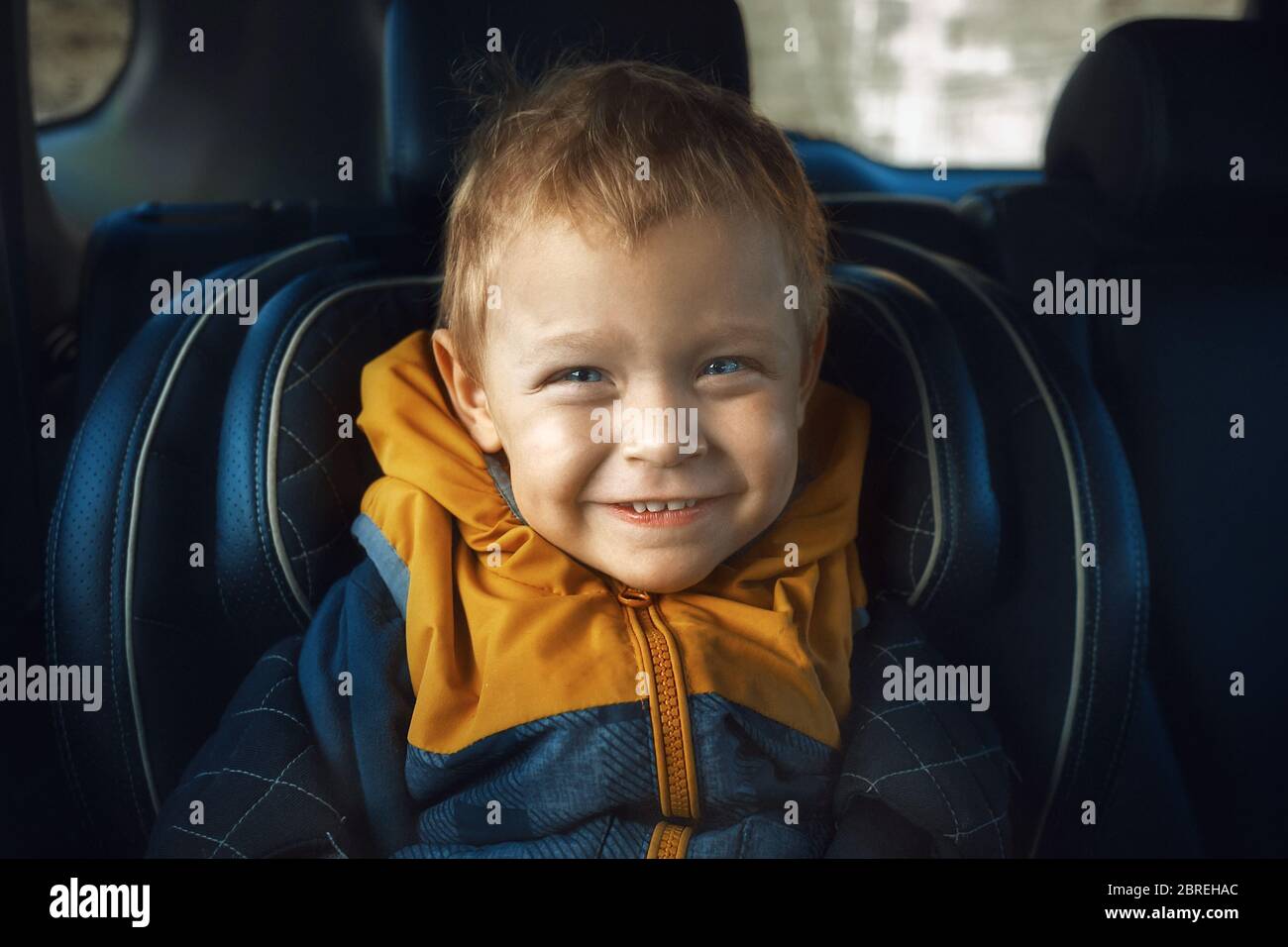 Ein fröhlicher kleiner Junge lächelt auf dem Kindersitz. Sicherheit von Kindern beim Fahren Stockfoto