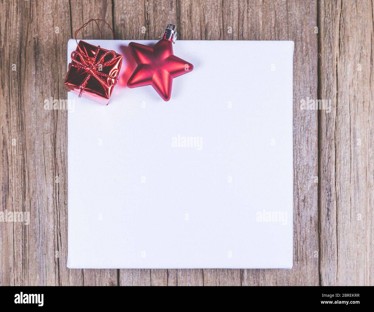 Weiße Leinwand Raum Rahmen mit Weihnachtsschmuck auf Holzplatte, bereit für Produktdisplay Montage. Stockfoto