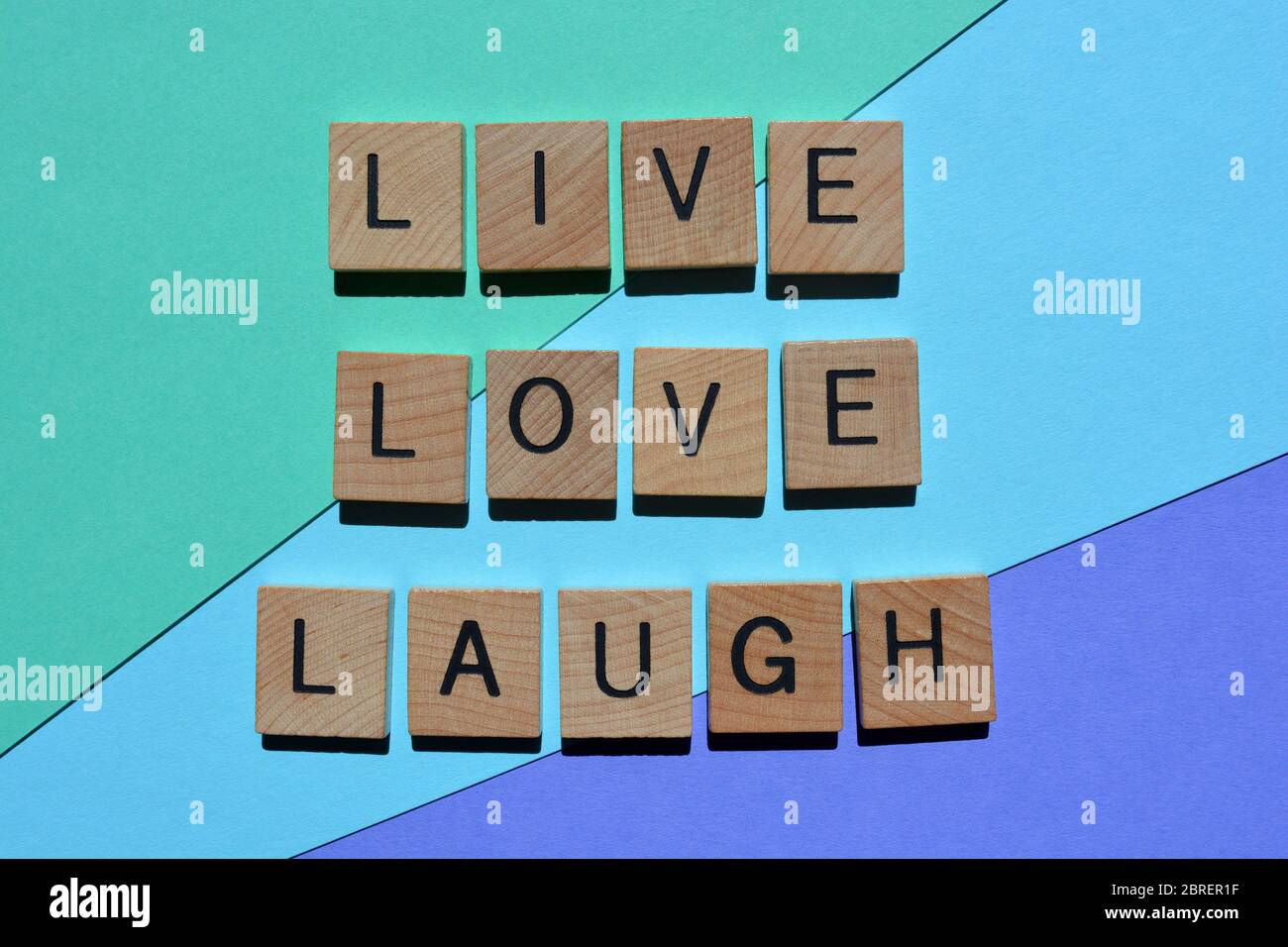 Leben, Liebe, Lachen, Wörter in hölzernen Buchstaben isoliert auf blauem Hintergrund Stockfoto