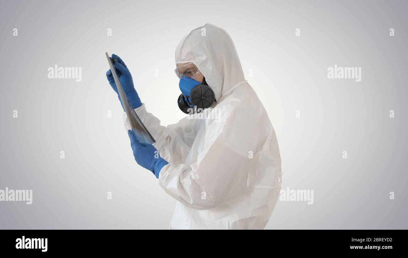 Epidemiologe in Atemschutzmaske untersuchen die Pneumonie des Patienten auf einem Röntgenbild Covid-19 auf Gradientenhintergrund. Stockfoto