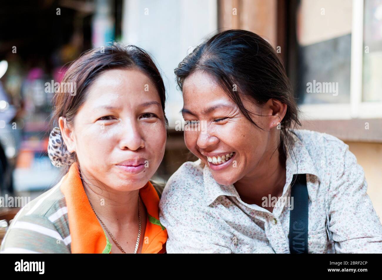 Zwei kambodschanische Schwestern lachen zusammen auf dem Psar Nat Markt, Battambang, Kambodscha, Südostasien Stockfoto