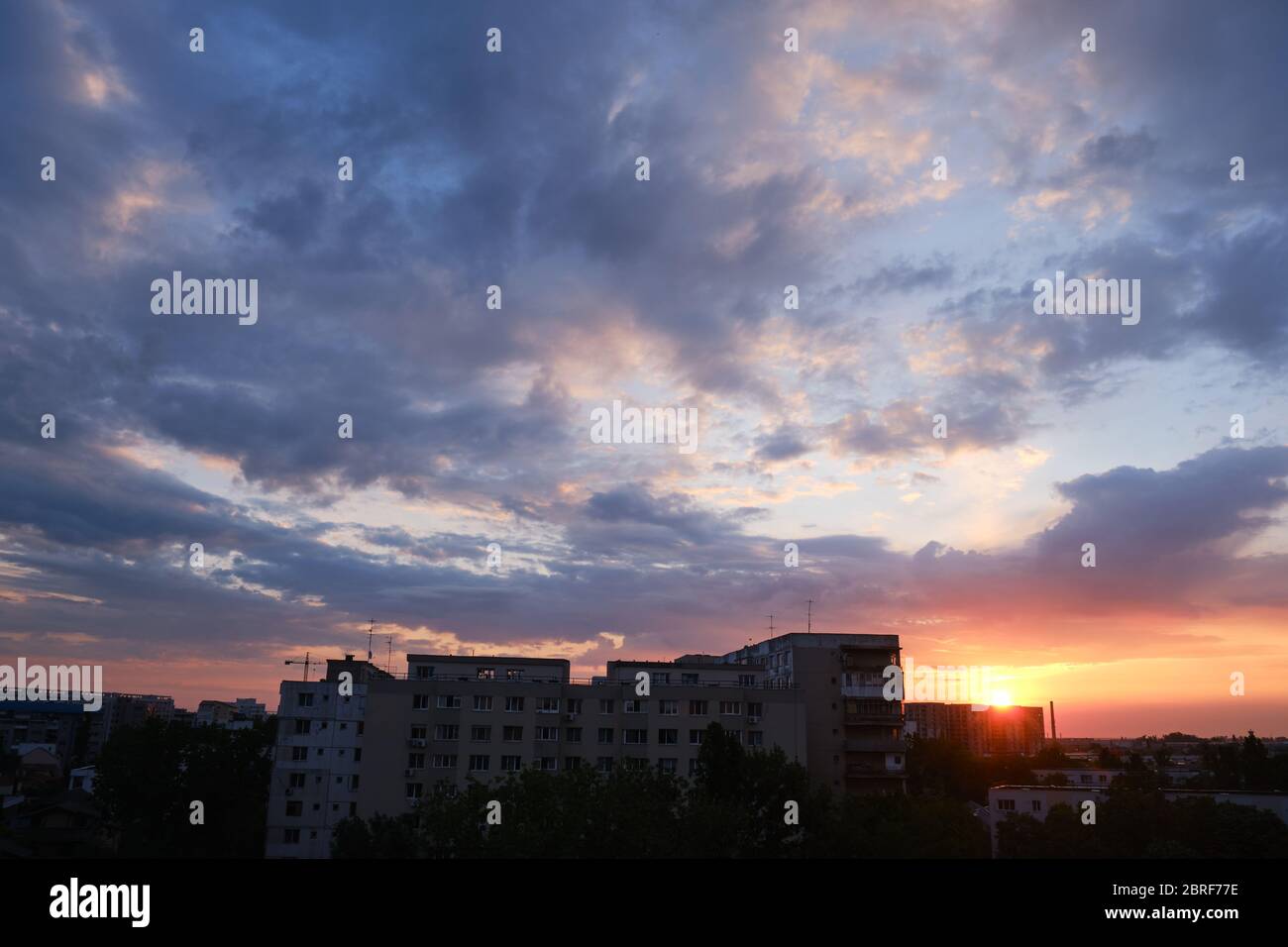 Städtischer Sonnenaufgang mit violetten und orangefarbenen Wolken am Himmel, nach einem Sturm, in Bukarest, Rumänien. Stockfoto