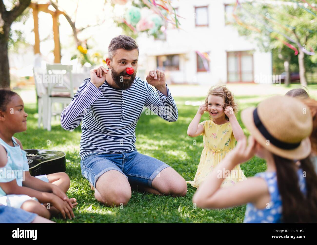 Mann mit kleinen Kindern auf dem Boden im Garten im Sommer, spielen. Stockfoto