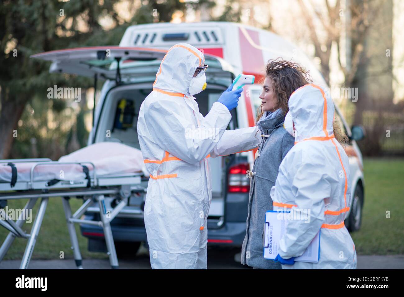 Menschen mit Schutzanzüge helfen Frau im Freien, Coronavirus-Konzept. Stockfoto