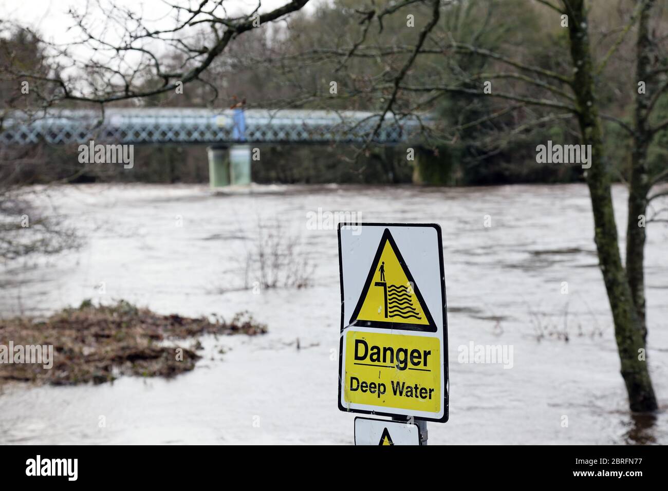 Die Tees in Hochwasserbedingungen mit einem Gefahrenzeichen Tiefwasser und die Deepdale Aqueduct Bridge dahinter, Barnard Castle, Grafschaft Durham, Großbritannien Stockfoto