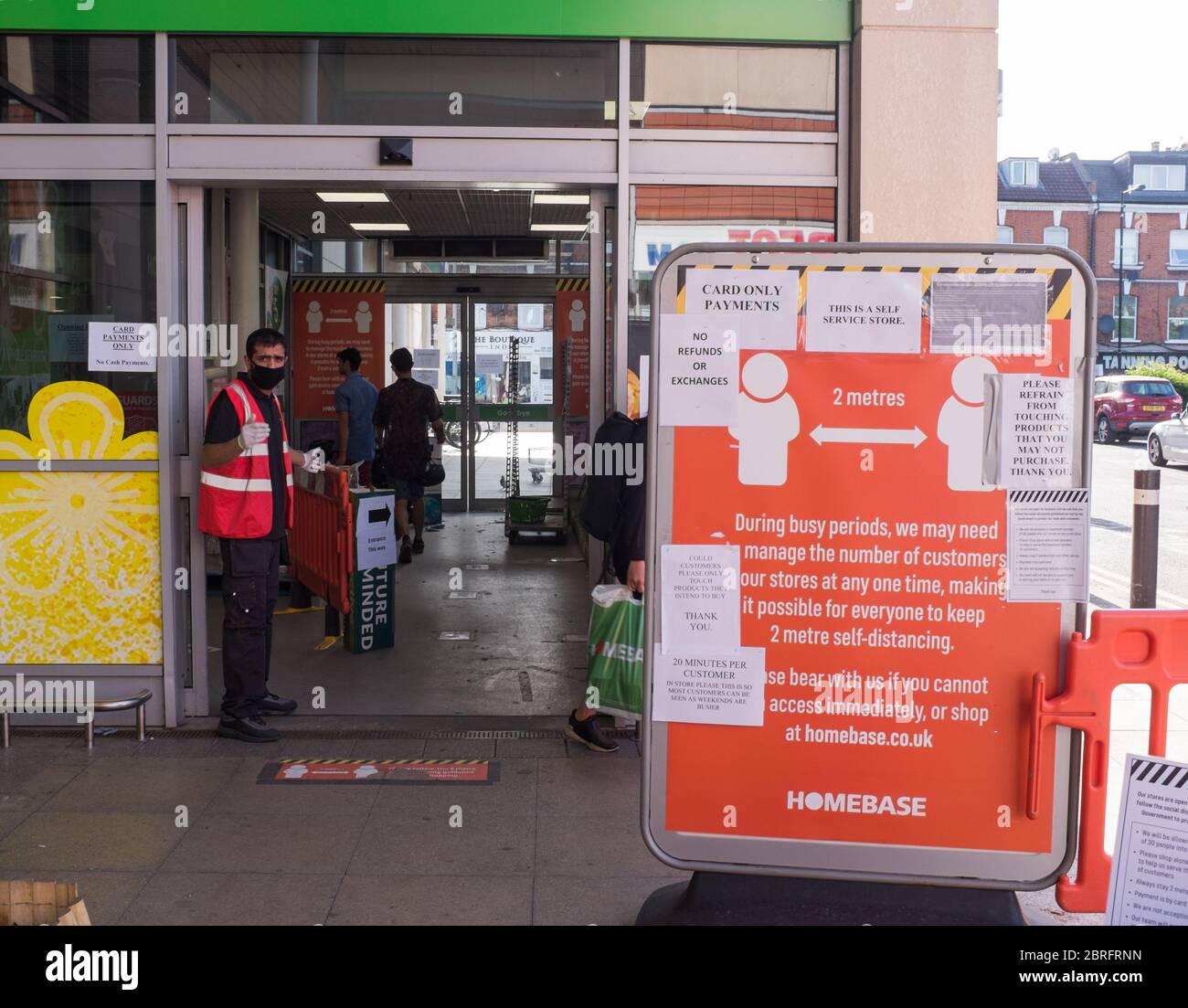 Ein Wachmann reguliert die Kunden, die während der Pandemie-Krise des Coronavirus in eine Filiale von Homebase in Nord-London einreisen Stockfoto