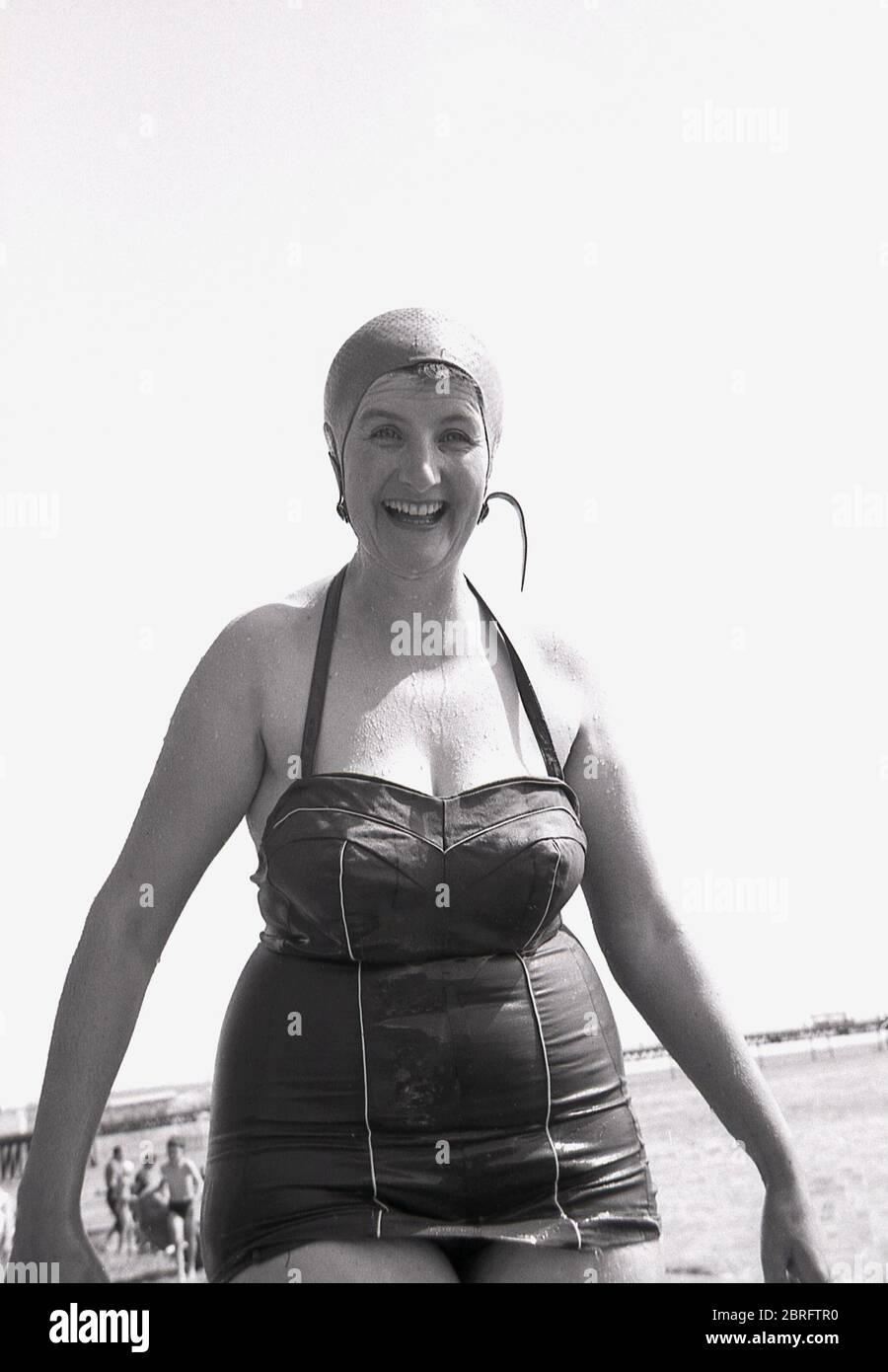 1961, historisch, eine reife, eher unverschämtere Dame in einem nassen Badeanzug und Gummibadehut lächelnd, gerade im Meer schwimmen, England, UK. Stockfoto