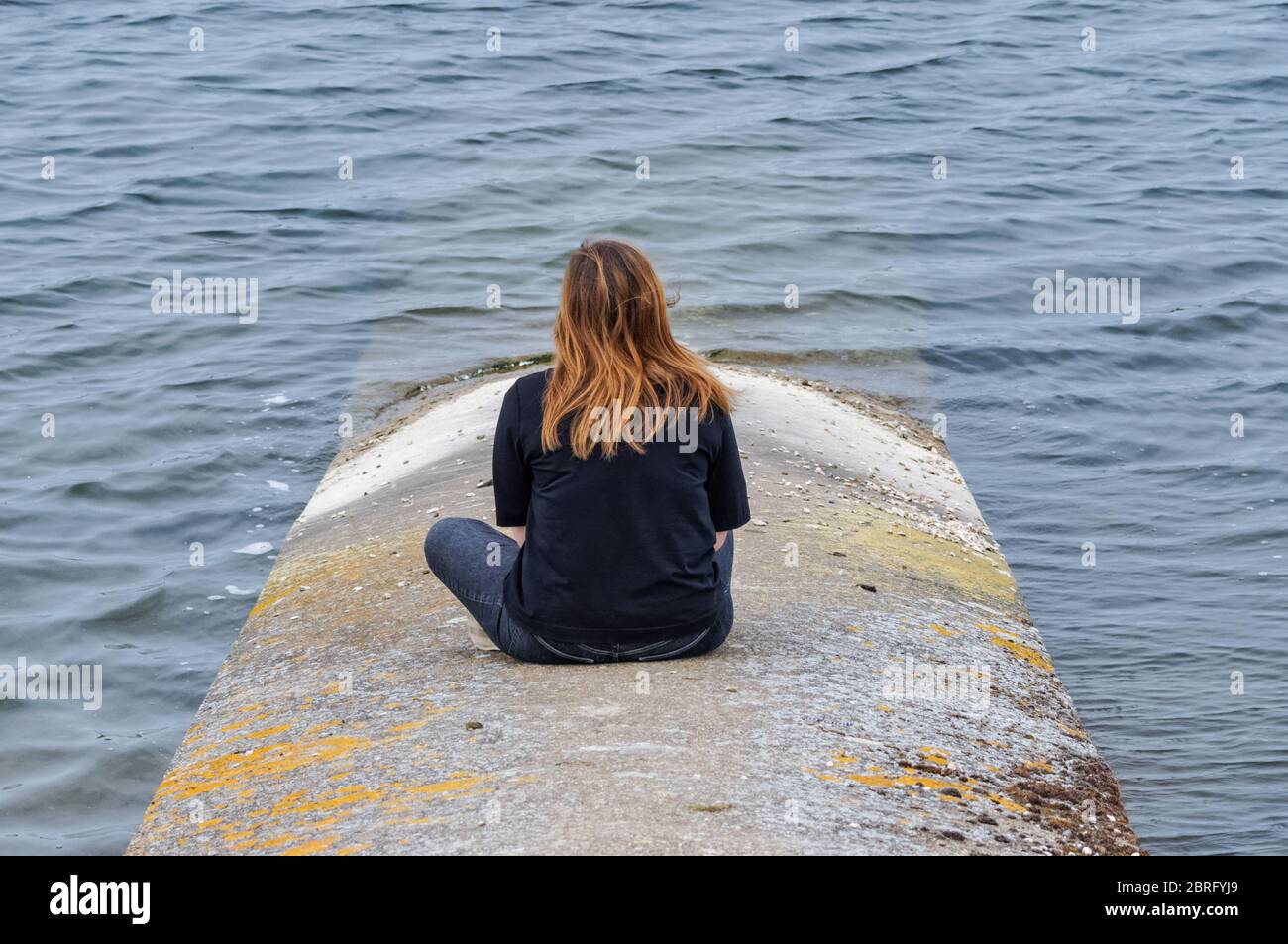 Einsames Mädchen sitzt und schaut auf den See Stockfoto