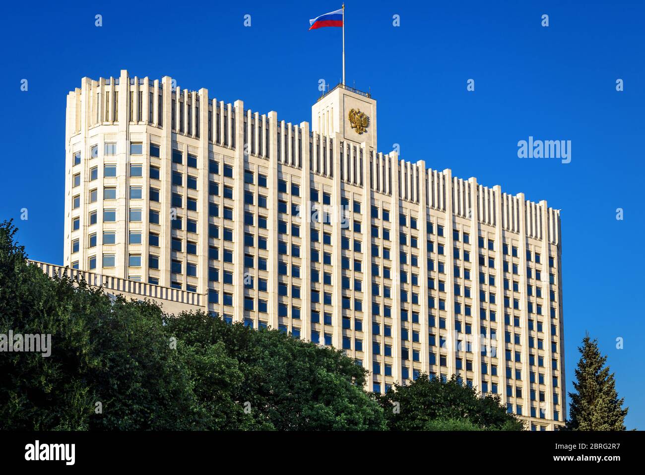 Haus der Regierung der Russischen Föderation (Weißes Haus) im Sommer, Moskau, Russland. Landschaftlich schöne Aussicht auf das Regierungsgebäude mit Wappen Stockfoto