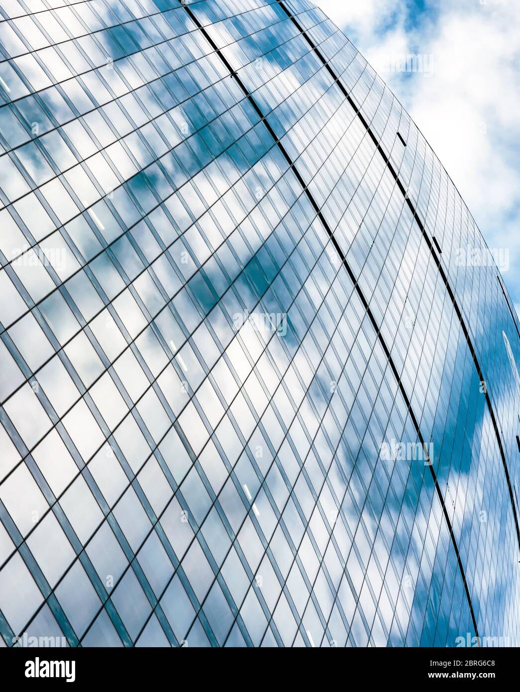 Abstrakter Architekturhintergrund. Der blaue Himmel spiegelt sich in einer Fassade des Bürohochhauses wider. Design aus Stahl und Glas. Konzept von Business und Finanzen. Stockfoto