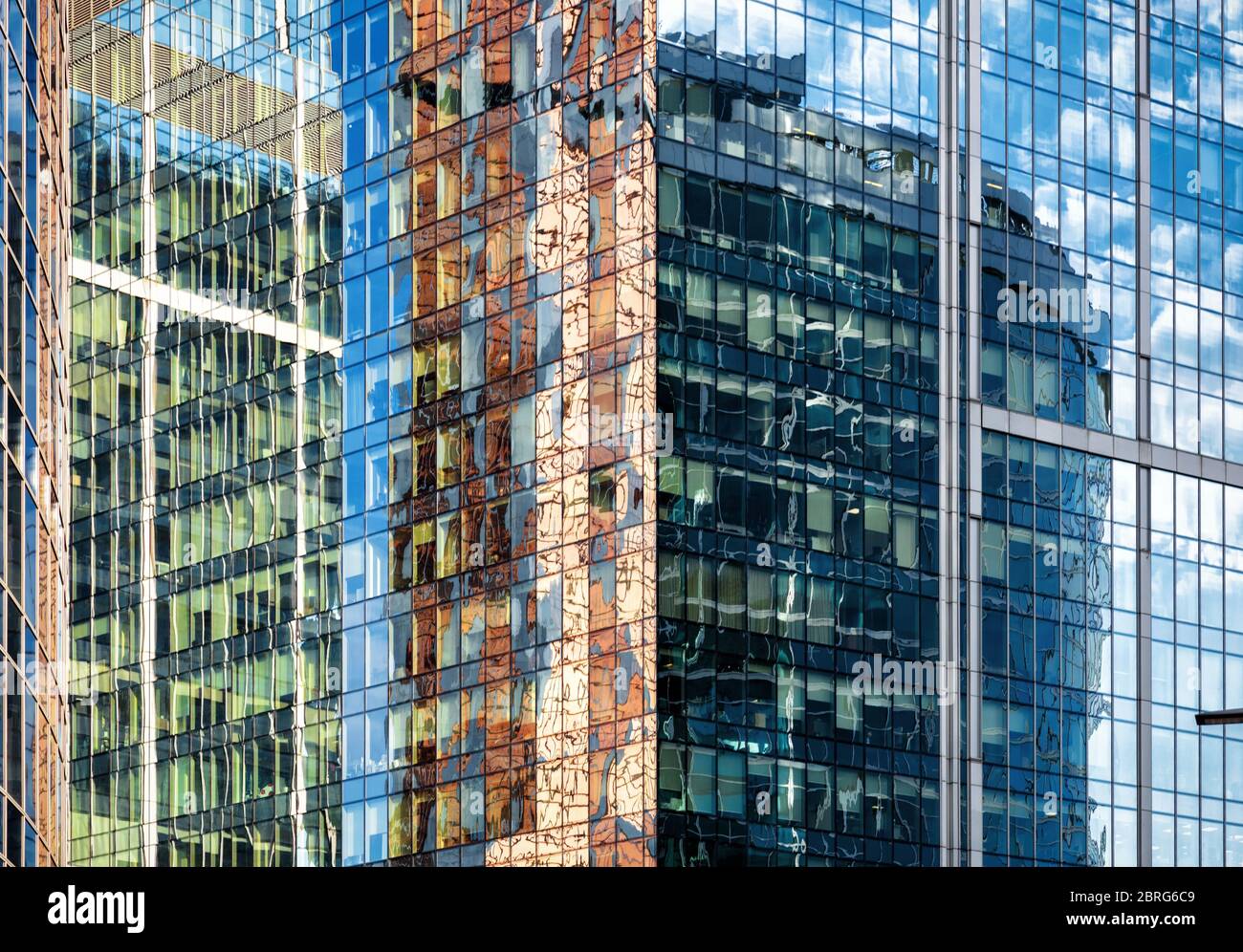 Abstrakter Architekturhintergrund. Himmel und Gebäude spiegeln sich in der Bürohochhaus-Fassade wider. Konzept der modernen Konstruktionen und Wirtschaft. Sehr Stockfoto