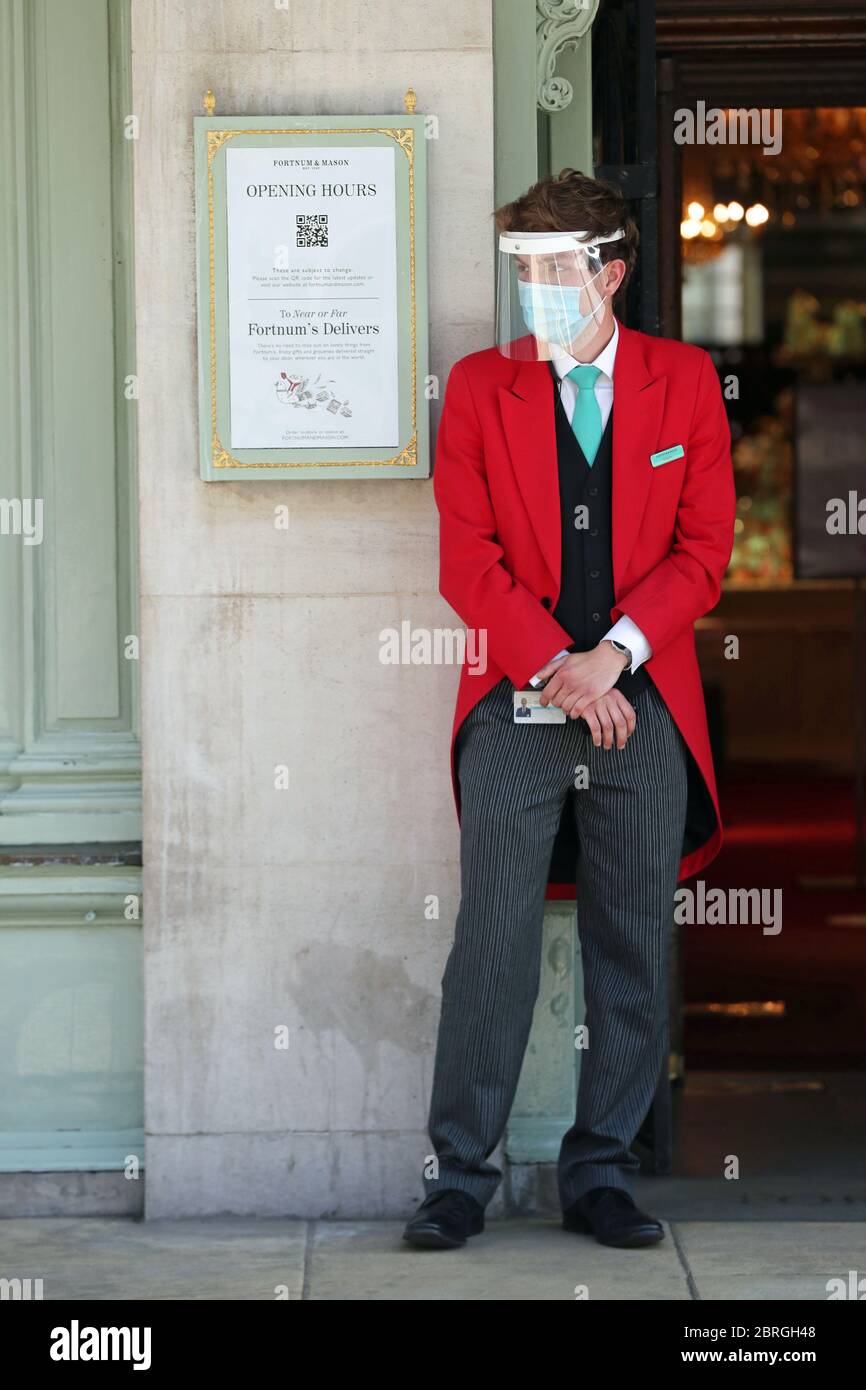 Ein uniformierter Türsteher trägt eine Maske und ein Visier vor dem Eingang des Kaufhauses Fortnum & Mason in Piccadilly, im Zentrum Londons, das seit heute zwei Food Halls für Kunden eröffnet hat, da die Beschränkungen für die Sperrung des Coronavirus gelockert werden. Stockfoto