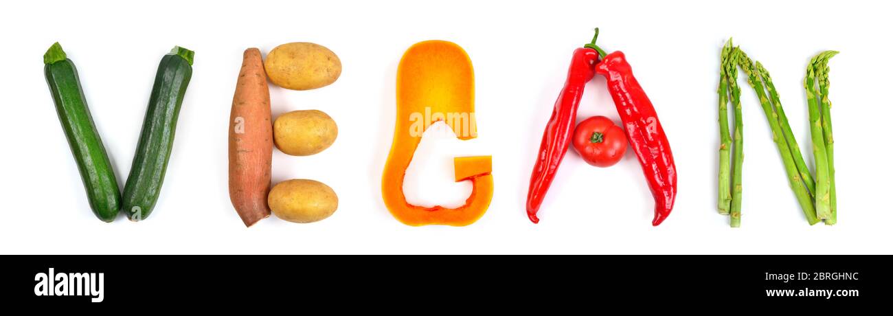 Der Schriftzug vegan arrangiert mit verschiedenem bunten Gemüse auf weiß: Zucchini, Kartoffeln, Butternusskürbis, rote Paprika und Spargel. Konzept Stu Stockfoto
