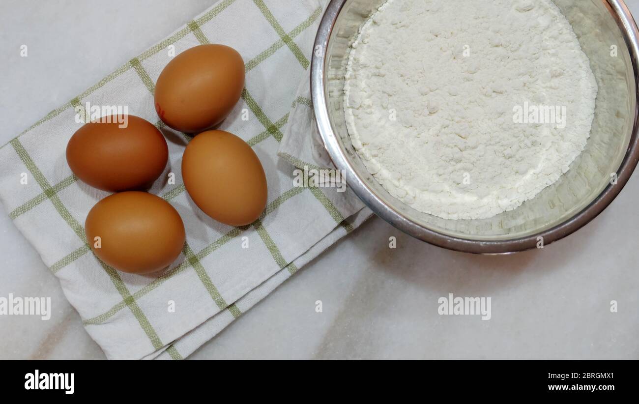 4 Braten Sie Eier auf einem weiß-grünen Küchentuch, und eine Schüssel mit weißem Backmehl an der Seite. Stockfoto
