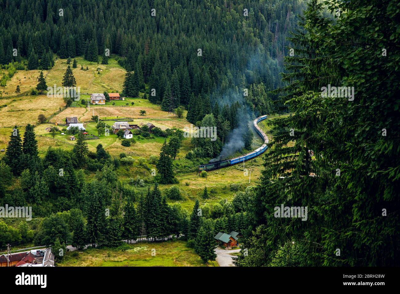 Ein langer Zug in den Bergen der Karpaten. Helle Landschaft und Zug. Stockfoto