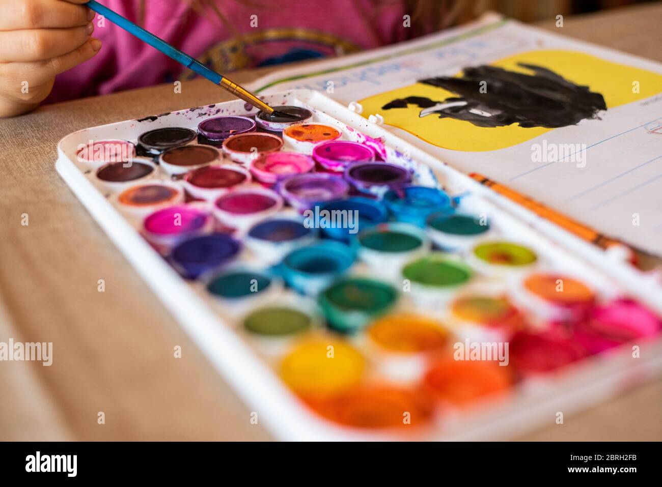 Ein 5-jähriges Mädchen malt mit einer Vielzahl von Aquarellfarben. Stockfoto