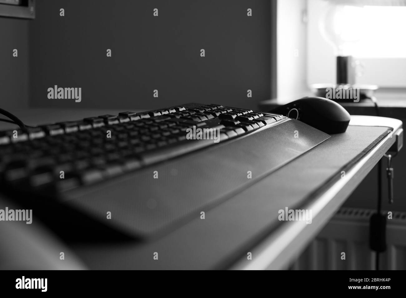Ein Schwarz-Weiß-Foto einer Tastatur und Maus auf einem Schreibtisch ohne Personen im Home Office. Zeigen das Gefühl der Einsamkeit bei der Arbeit von zu Hause du Stockfoto