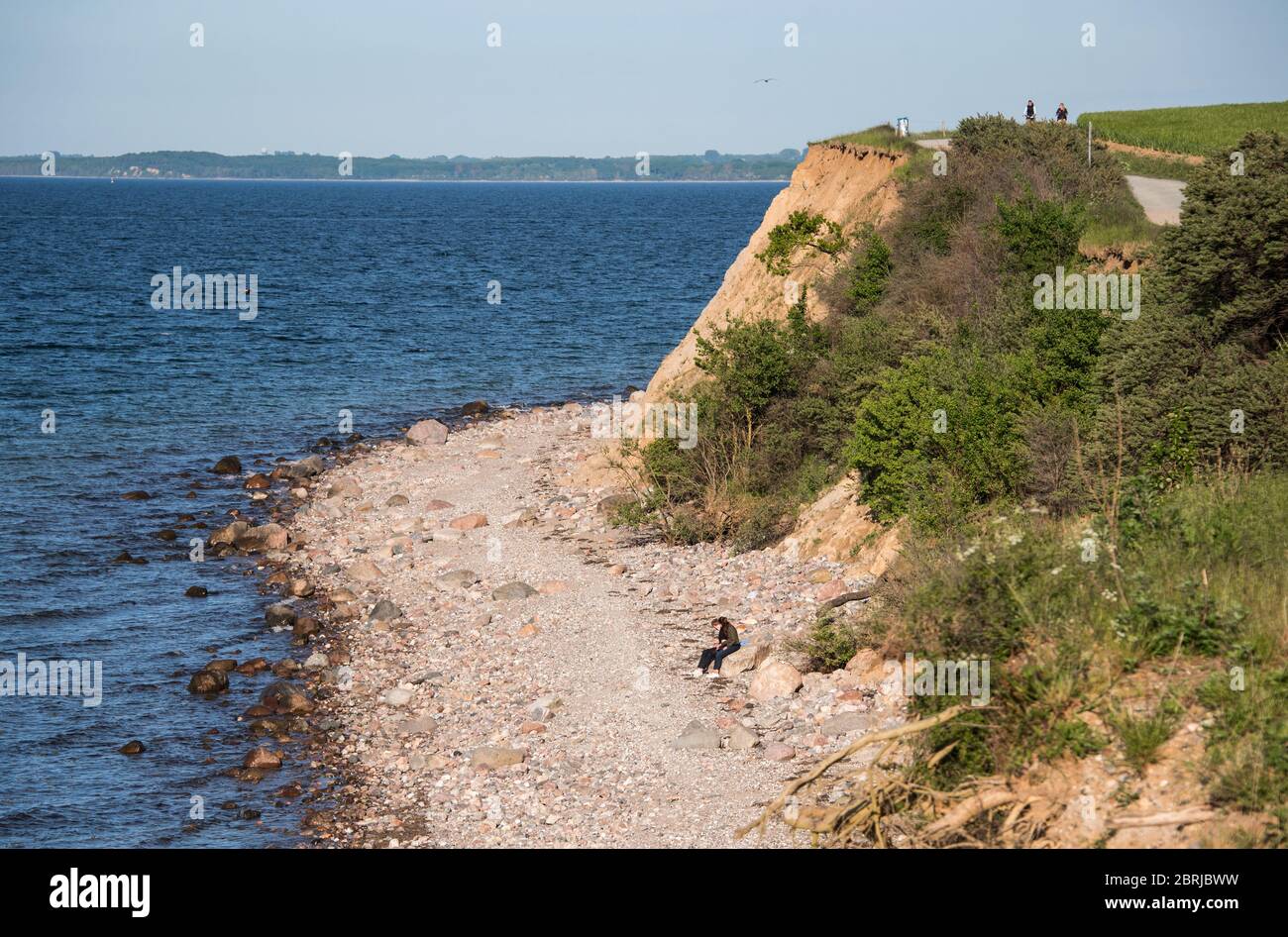 21. Mai 2020, Schleswig-Holstein, Lübeck-Travemünde: Ein Paar sitzt am Brodtener Steilufer am Ostseestrand, zwei Radfahrer sind an der Steilküste unterwegs. Foto: Daniel Bockwoldt/dpa Stockfoto