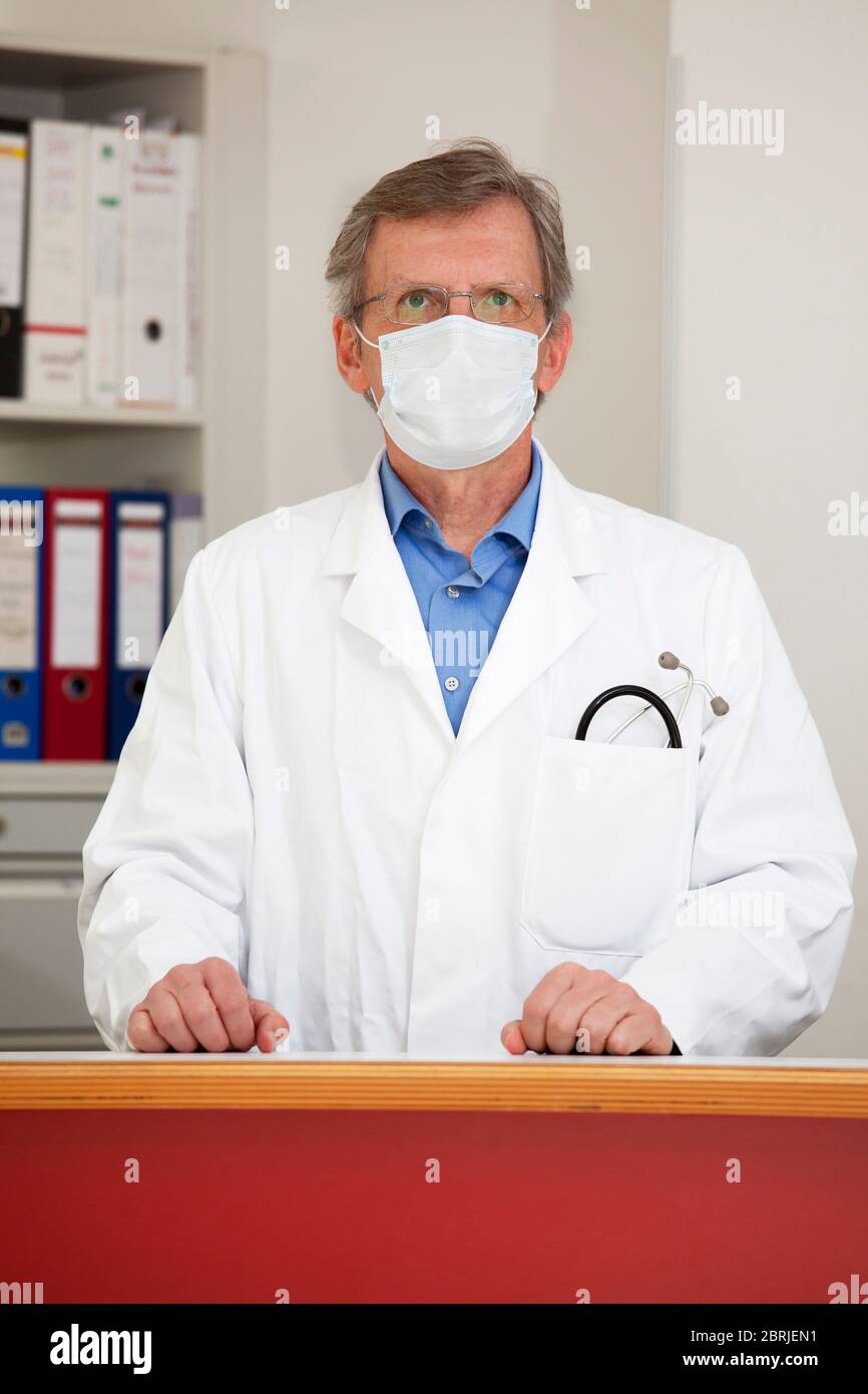 Arzt mit medizinischer Maske an der Rezeption eines Krankenhauses - Fokus auf das Gesicht Stockfoto
