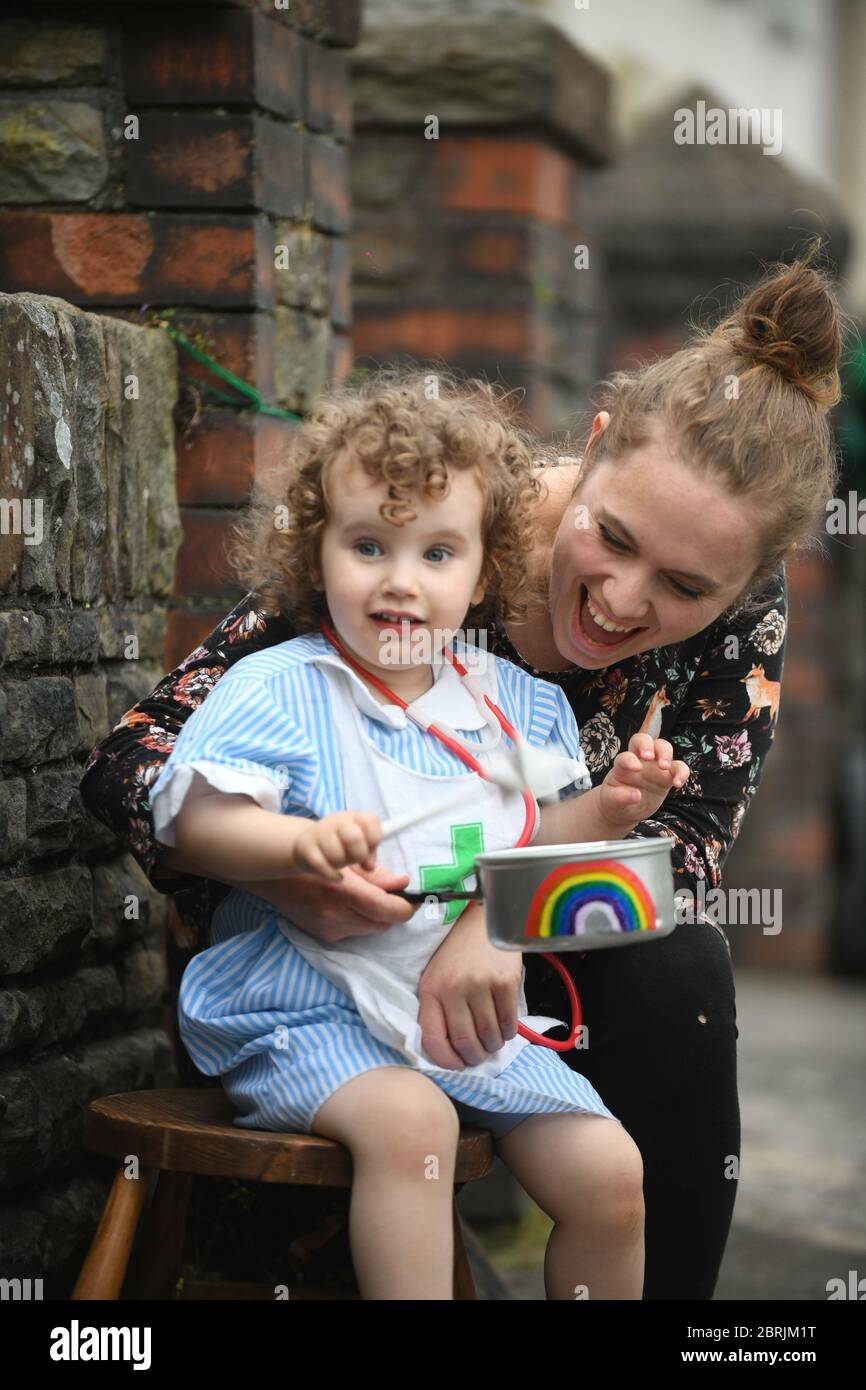 Swansea, Wales, Großbritannien. Mai 2020. Die zweijährige Lillian Joy aus Swansea kleidet sich als kleine Krankenschwester und trifft eine Regenbogenbemalte Pfanne, um ihre Unterstützung für Schlüsselarbeiter und den NHS mit ihrer Mutter Bethan zu zeigen, während Clap für unsere Betreuer von außerhalb ihres Hauses. Quelle : Robert Melen/Alamy Live News. Stockfoto