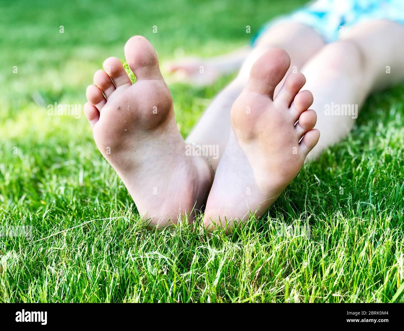 Kinderfüße auf grünem Gras in einem Sommerpark. Stockfoto