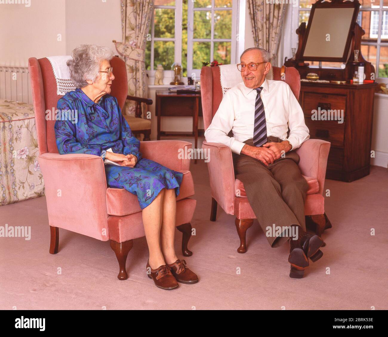 Ältere Frau und Mann, die im Pflegeheim, Surrey, England, Großbritannien, plaudern Stockfoto
