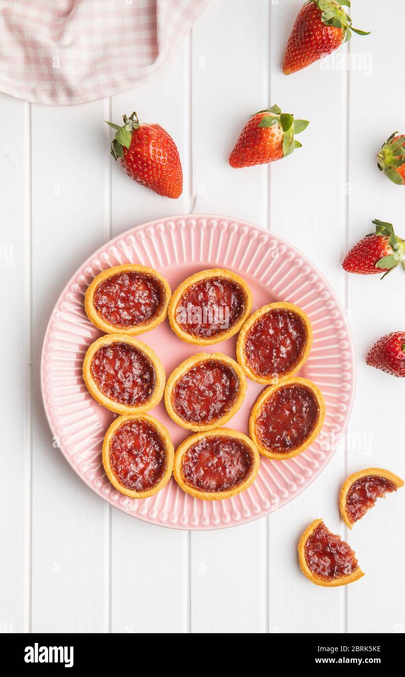Süße Kekse mit Erdbeermarmelade und Erdbeeren auf weißem Tisch. Draufsicht. Stockfoto