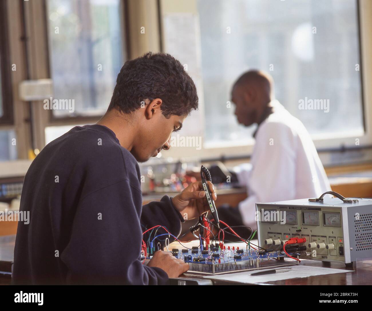 Schwarzer Student, der an Geräten in der Elektronikklasse arbeitet, Surrey, England, Großbritannien Stockfoto
