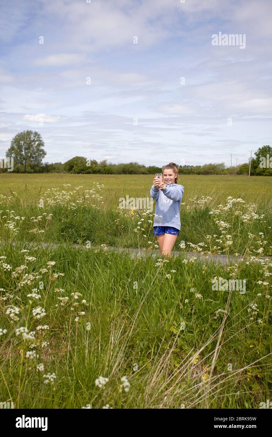 Junges Mädchen mit ihrem iPhone, um ein Foto auf dem Land, großbritannien Stockfoto