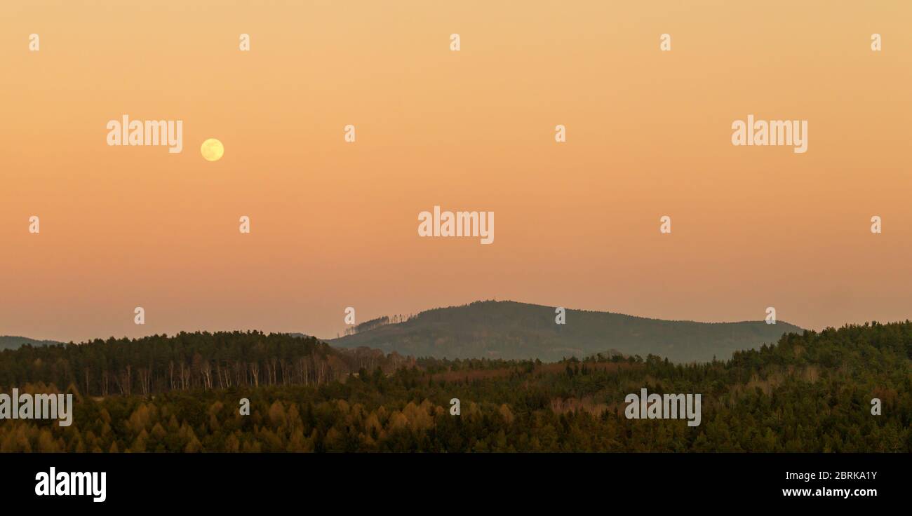 Abends hügelige Landschaft bei Vollmond Stockfoto